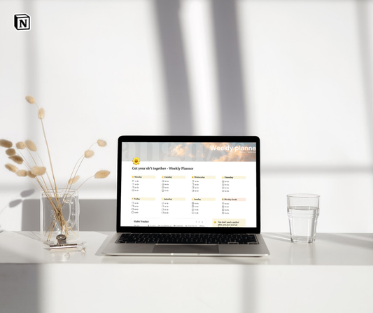 Laptop on a desk with a weekly planner app open on the screen, minimalistic setting.